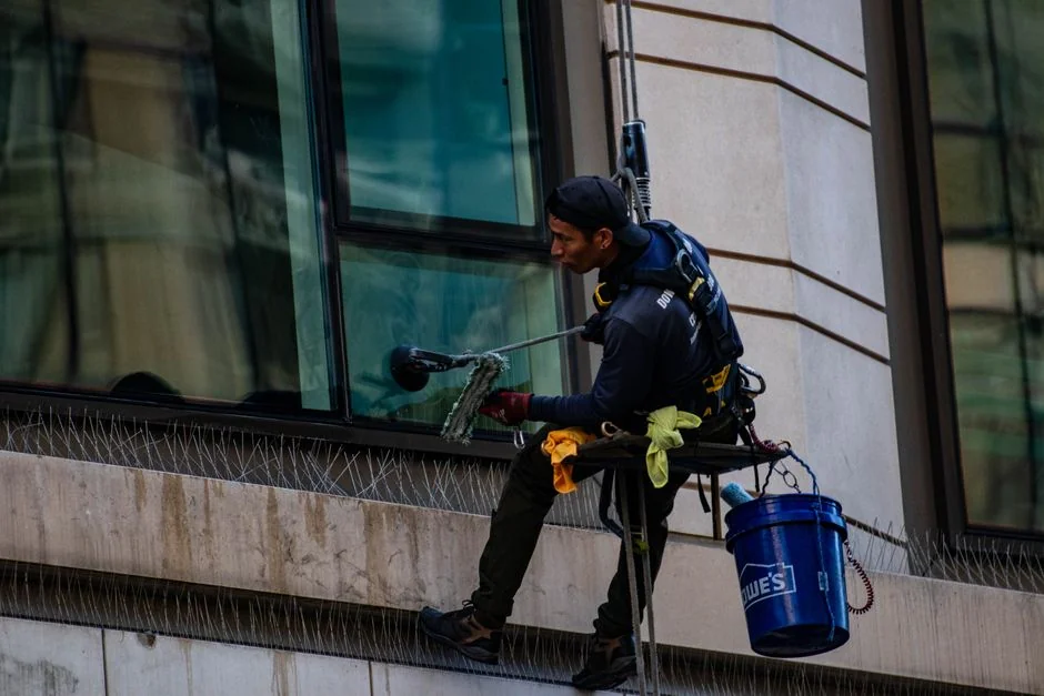 journey-01 A male window cleaner is washing the outside glass roof from above with a tool in daylight.